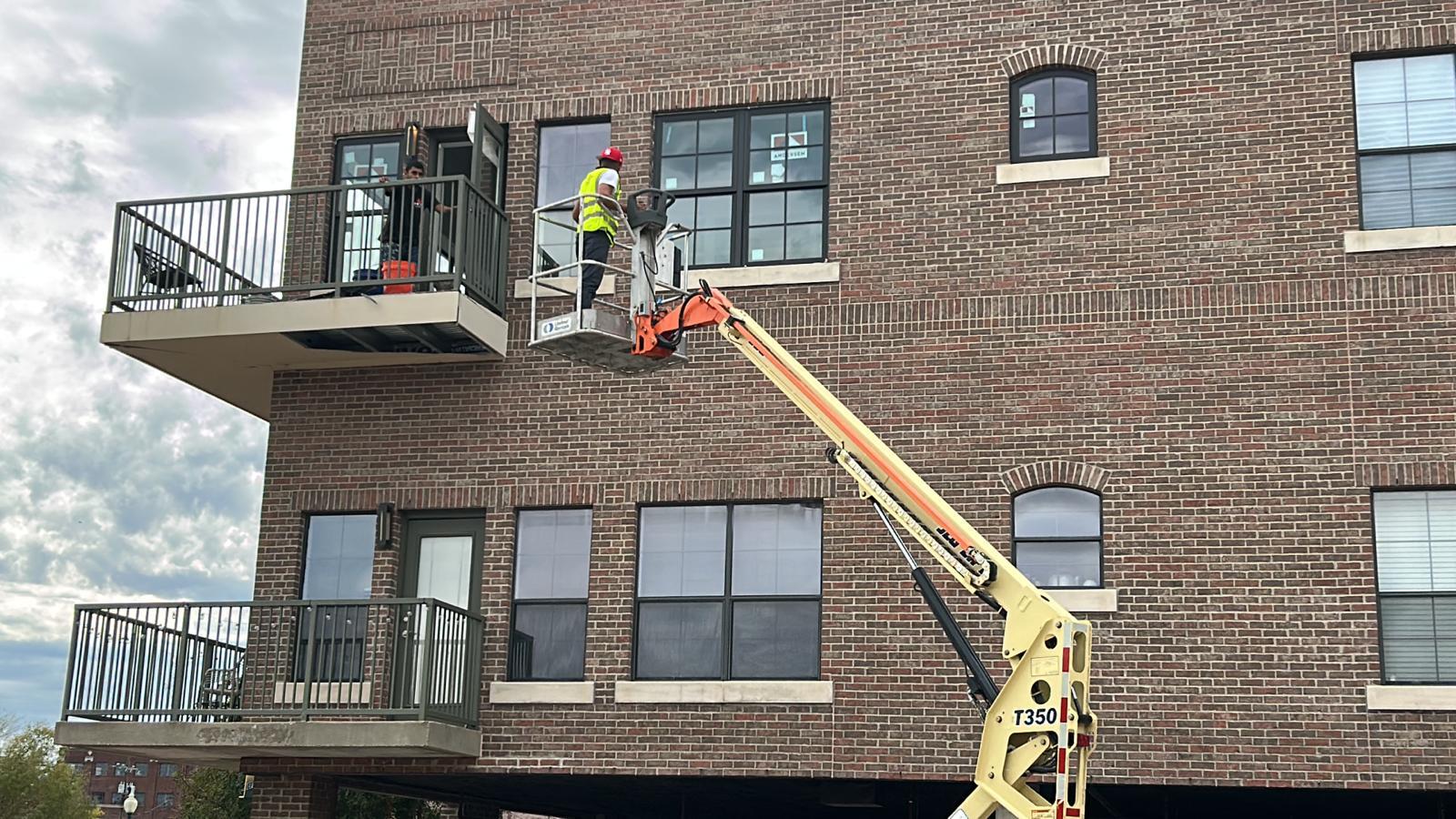 Star One Remodeling crew using a boom lift for a multi-story condo window installation in Waco
